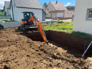 Mini-pelle creusant une fouille de terrassement près d’une maison