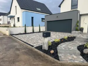 Allée pavée courbe et massifs en paillage d’ardoise devant un garage
