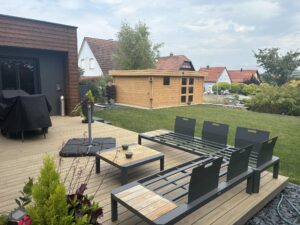 Terrasse en bois avec salon de jardin, pelouse et abri de jardin