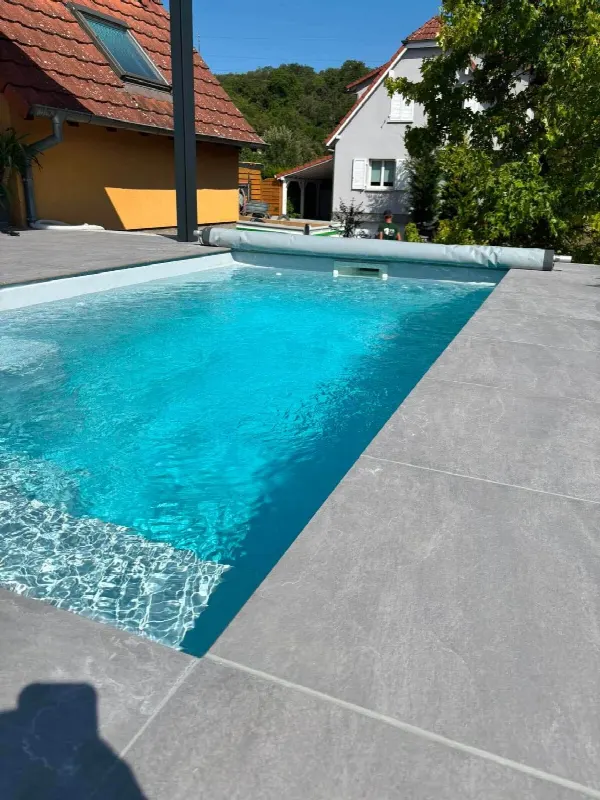 Piscine à l’eau turquoise entourée d’un dallage gris