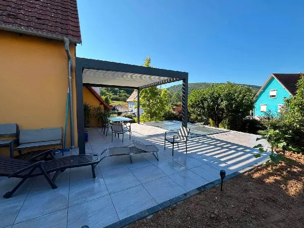Terrasse en grandes dalles grises avec pergola bioclimatique