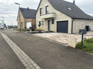 Allée en enrobé bordée de pavés devant une maison individuelle